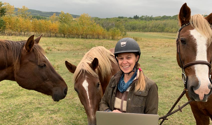 Dr. Carolyn Willekes, PhD, posing between two horses.