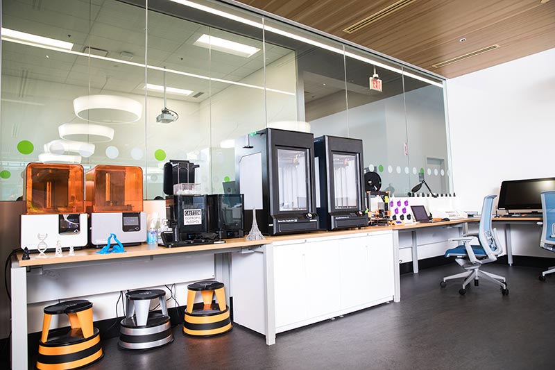 A desk with a small suite of 3D printers in Mount Royal University's Maker Studio.