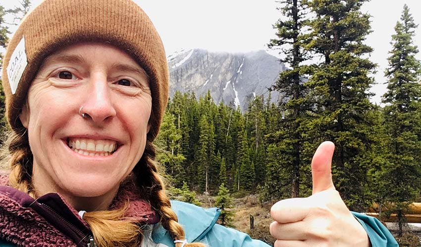 Selfie of Dr. Andria Dawson, PhD giving a thumbs up in the mountains.