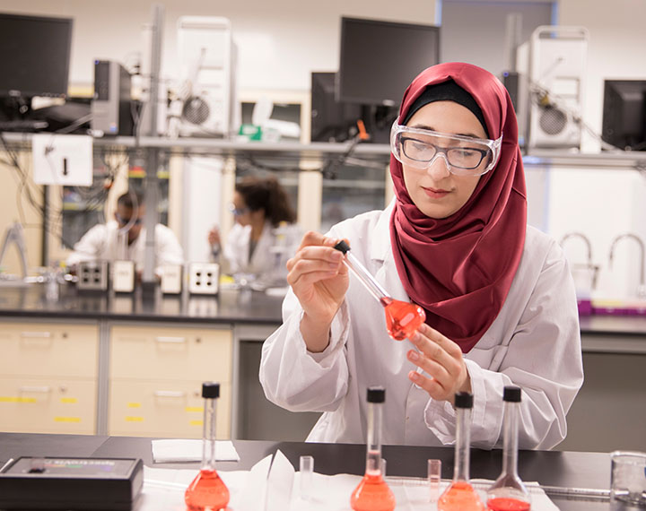 Student in a bright pink hijab working in one of MRU's chemistry labs.
