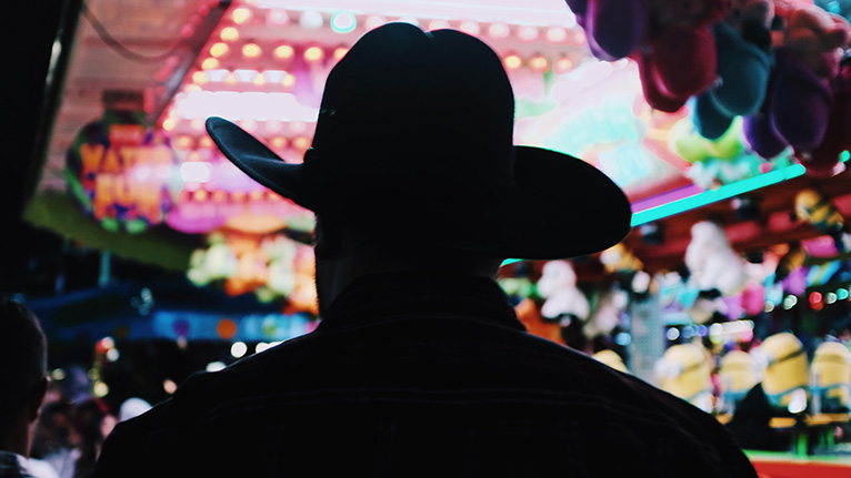 A person wearing a cowboy hat silhouetted against a fairway game.