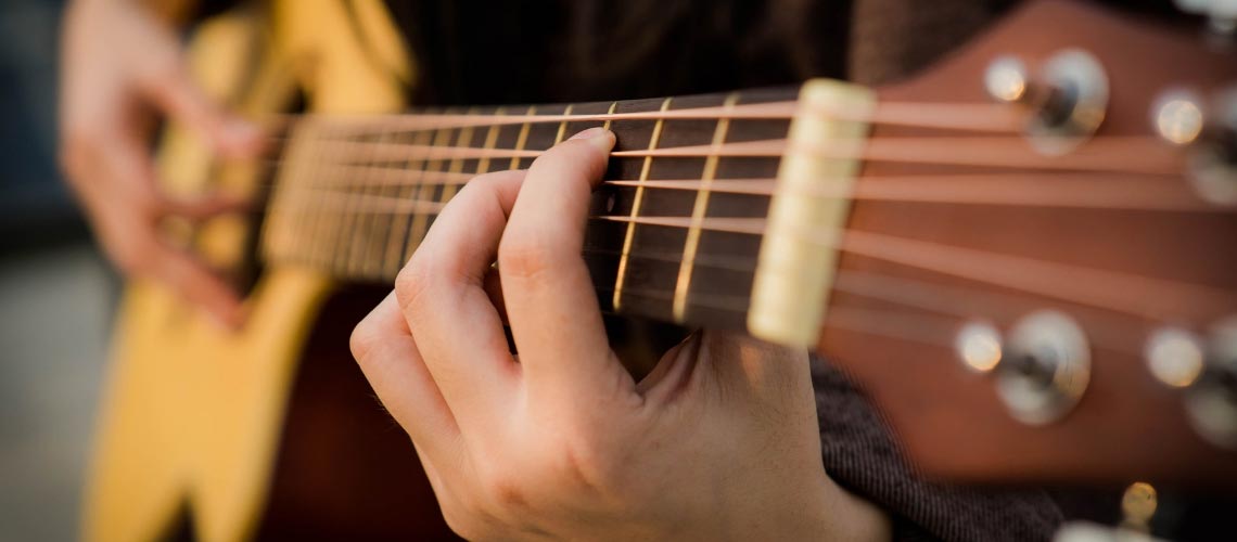 Fingers in position on a guitar.