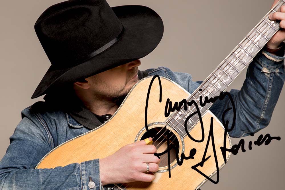 Paul Brandt holds a guitar close and strums the strings gently