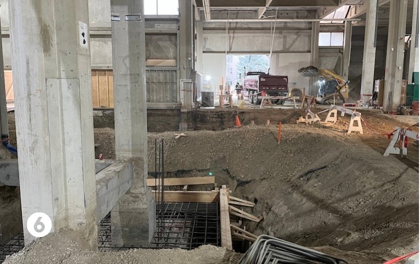 Photo 6 shows excavation around a support pillar with a large dump truck driving out of an opening in the building envelope. 