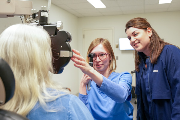 An optomestrist and assistant conducting an eye exam on a patient.