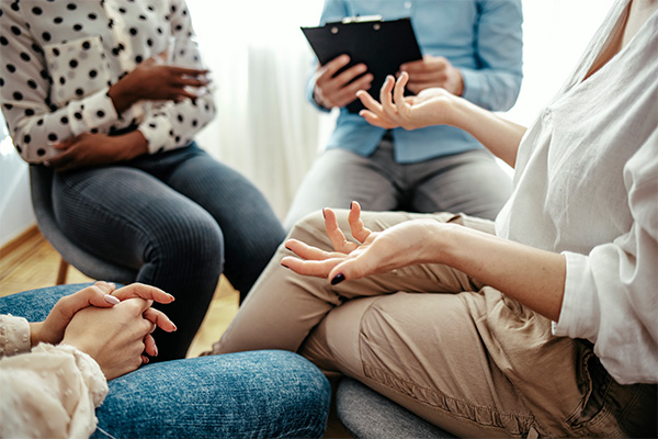 A group of people sit in a circle during group therapy.