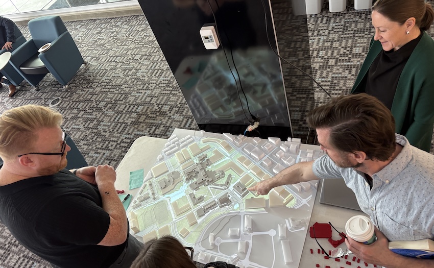 Participants review projections overlaid on a 3D model of campus that various patterns (pedestrian, vehicle, etc.) and potential areas of development and evolution (Residence district, perimeter, Main Building, etc.). 