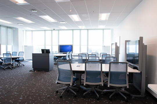 Photo of the Academic Development Centre multimedia classroom. Pods of desks are faced around large screens.
