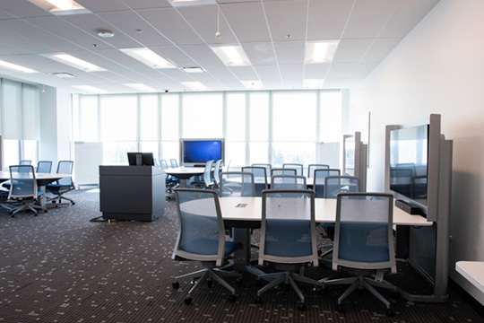 Photo of the Academic Development Centre multimedia classroom. Pods of desks are faced around large screens.