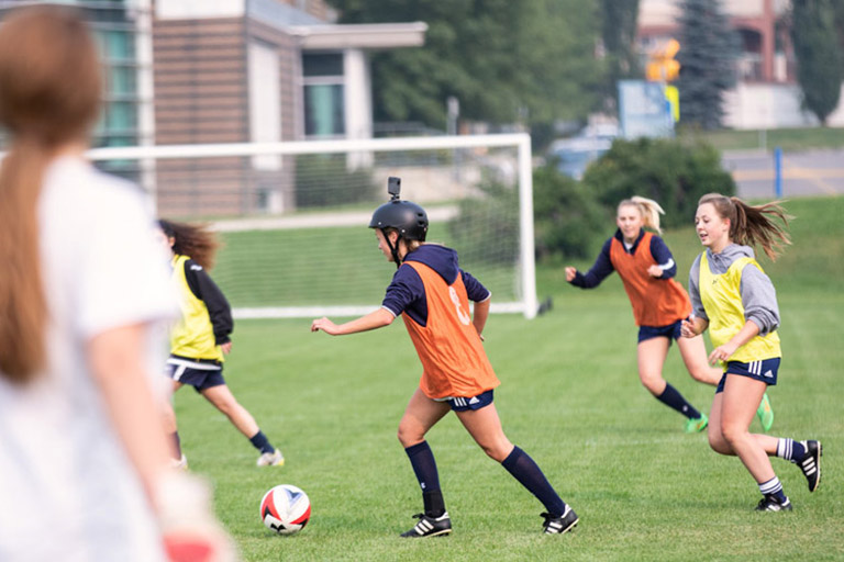 Mount Royal University's women's soccer team - one of the players is wearing a helmet that has a go procamera attached.