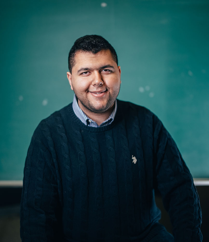 Haider Amin in front of a chalkboard in a classroom.