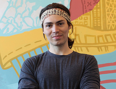 Ben Pearman with his arms crossing. He stands in front of a colourful background.