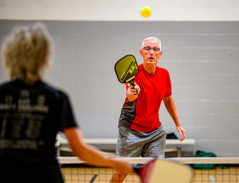 Two seniors play a leisurely game of pickleball.