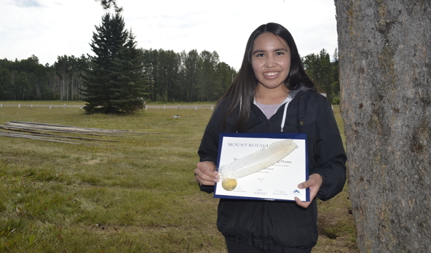 Stephanie Big Plume poses with her Education Assistant Certificate and a white eagle feather presented to her at a graduation event on the Tsuut'ina Nation.