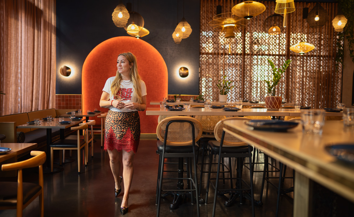 Amanda Hamilton in a restaurant, with a table and chairs visible around her,
