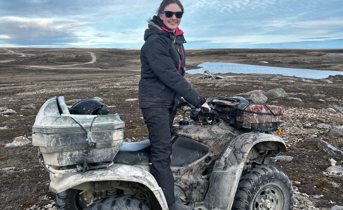 Ashley Lawson confidently rides a quad bike across a rugged terrain.