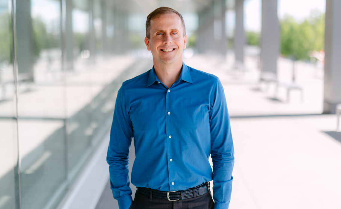 Brady Killough, PhD, stands confidently outside of the Riddell Library & Learning Centre.