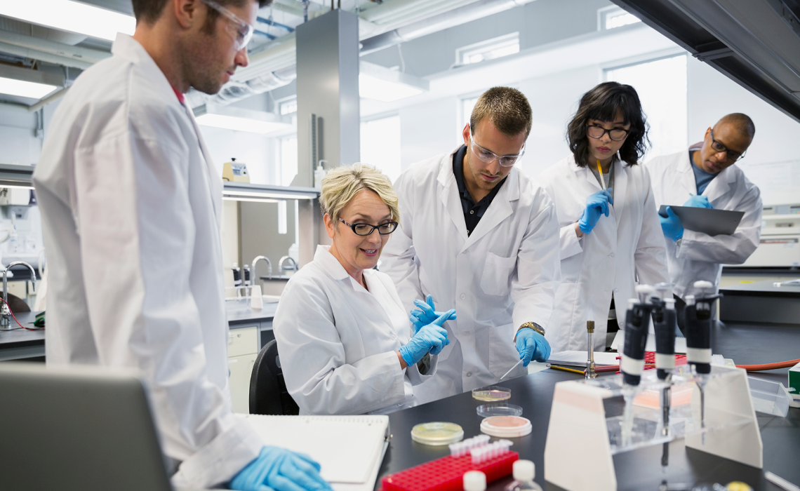 A group of people in lab coats collaborating on a scientific project in a laboratory setting.