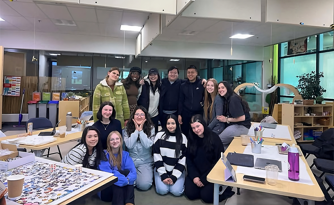 A group of MRU students smiling and posing together for a photo in a classroom setting.