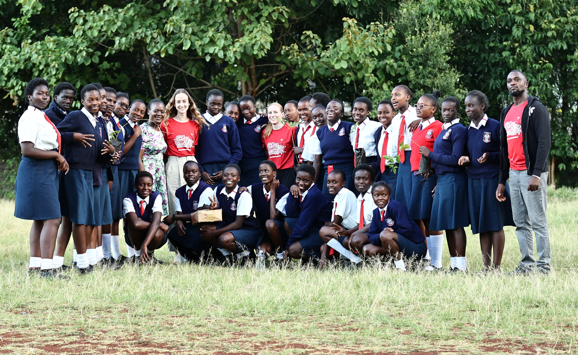 A group of young people smiling and posing together for a photo outdoors.