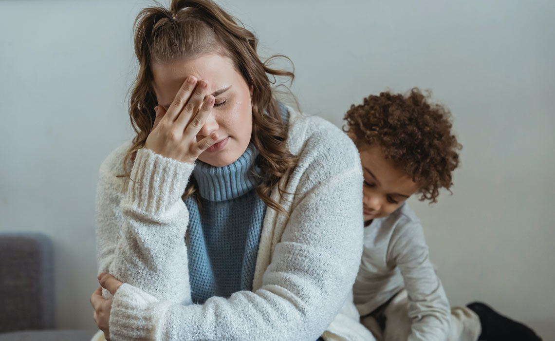 A tired woman sitting with her energetic child.