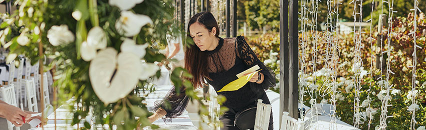 A woman organizing an event; setting up a table for an upcoming meal.