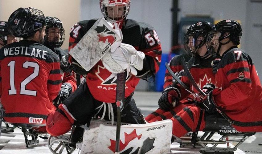 Adam Kingsmill on the ice surrounded by teammates.