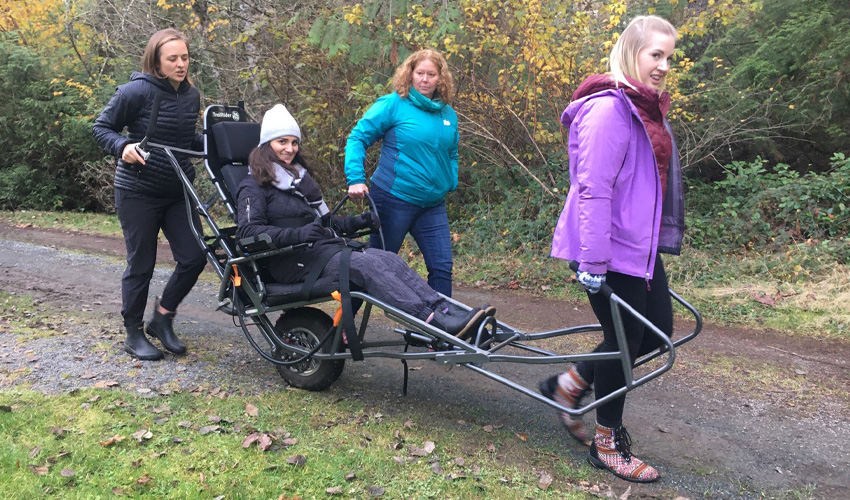 Photo of team pulling an adaptive, all-terrain wheelchair.