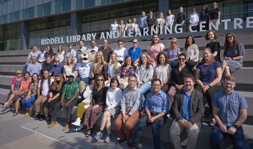 MRU's new faculty pose next to the Riddell Library and Learning Centre.