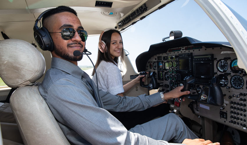 Two Mount Royal University Aviation students sitting in the cockpit of an airplane.