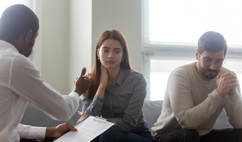 Male social worker talking to two people who look a upset.