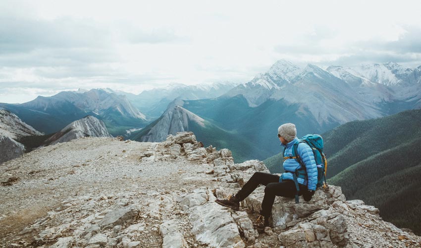 A hiker taking a moment to enjoy the view from the top of a mountain in Alberta.