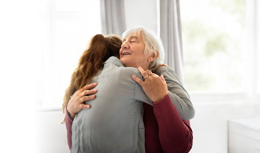A grandmother and adult granddaughter hugging.
