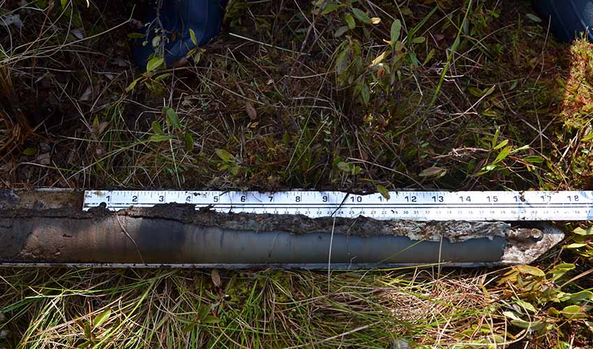 A ruler lined up against a cylinder of soil.