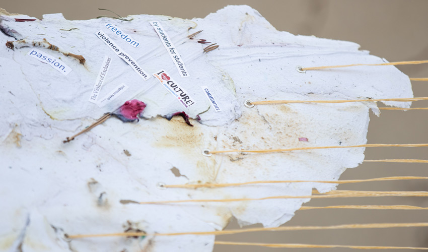 Close up photo of the paper-based art embedded with text with phrases like 'violence prevention, 'passion' and 'communities'.