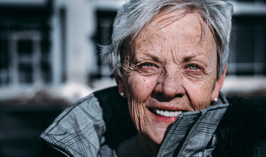 A happy, senior woman standing outside.