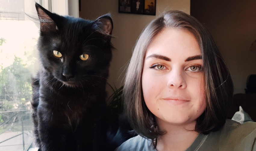 Kourtnee Burnett sitting next to a black cat.