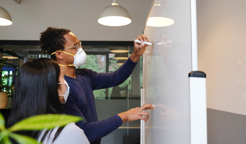 Two people planning and working in a post COVID-19 office setting.