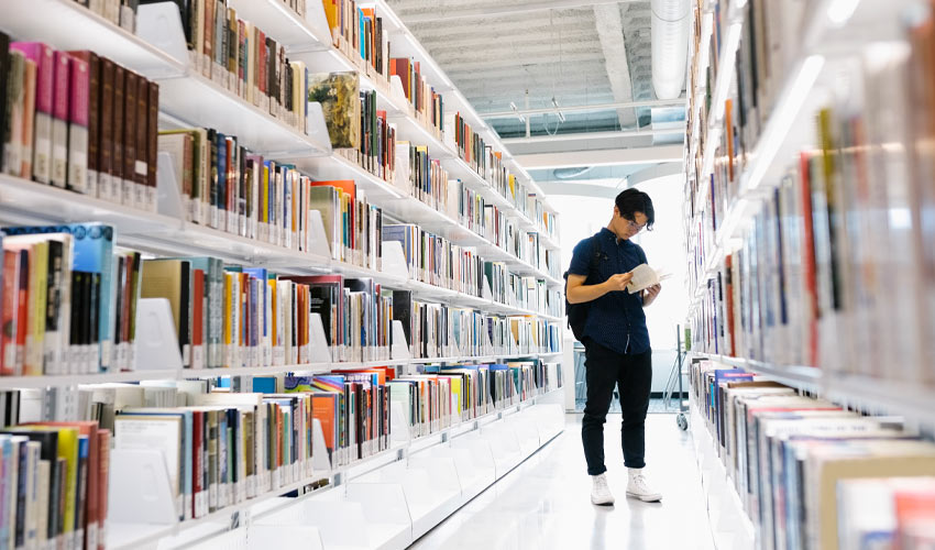 A student reading a book in the Mount Royal University Library.