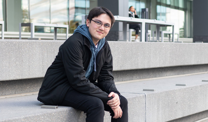 Matthew Fudge sitting outside the Riddell Library and Learning Centre.