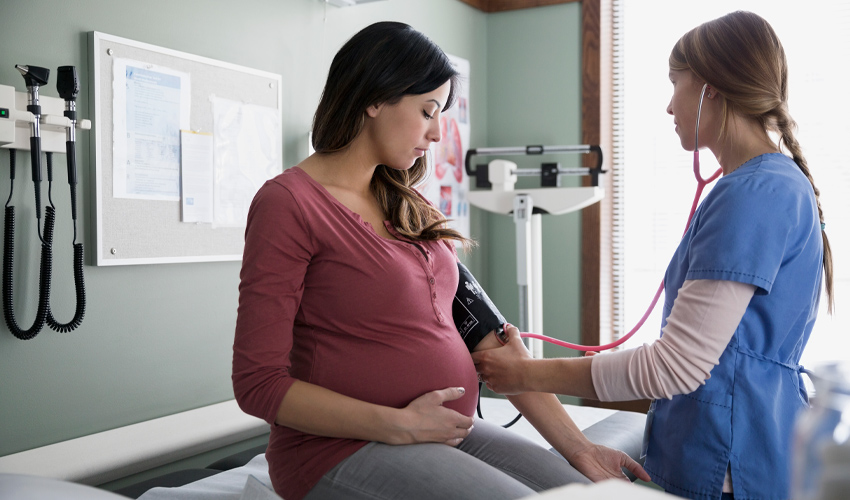 Photo of a nurse taking the blood pressure of pregnant woman.