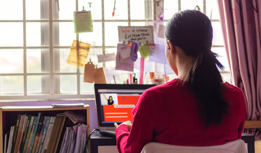 A woman working on a laptop from her home office.