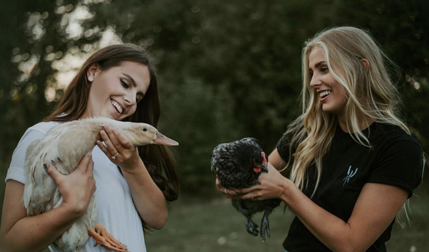 Taylor Pelland, left, holding a white duck and her sister, Quinn Pelland, holding a black chicken.