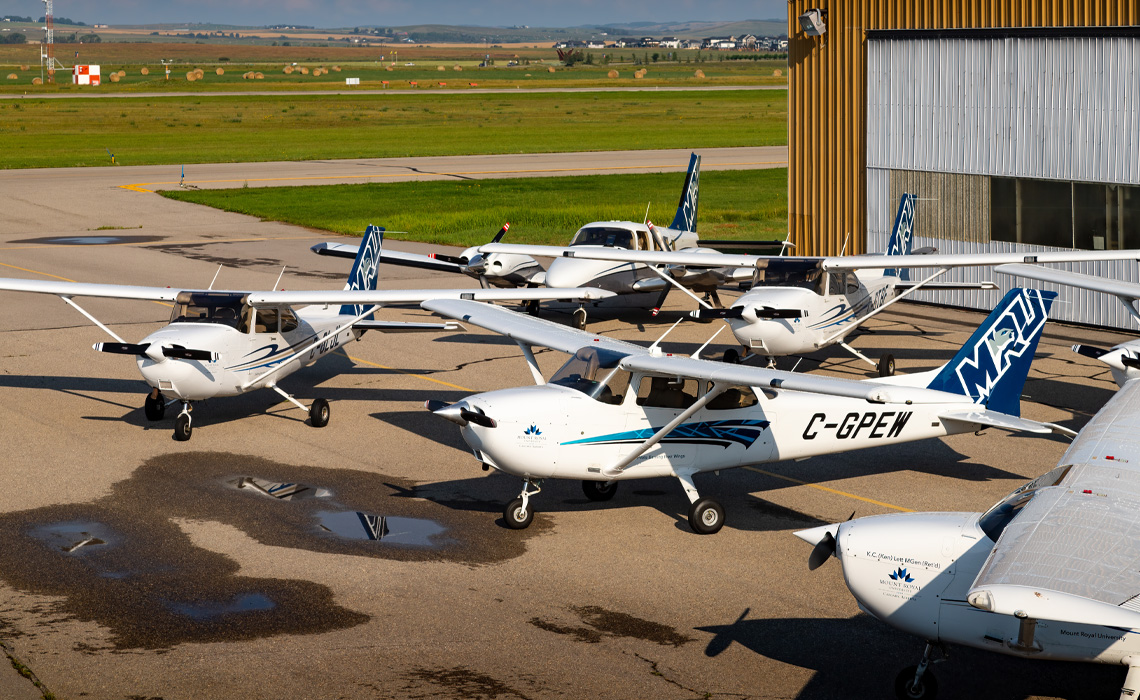 Seven MRU airplanes on the ground outside the Springbank hangar.