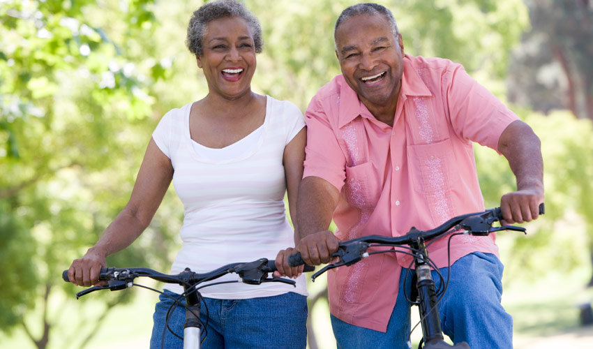 Two seniors cycling at a park.