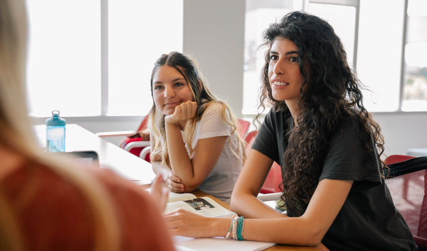 Photo of University students speaking to a professor in the Riddell Library and Learning Centre.