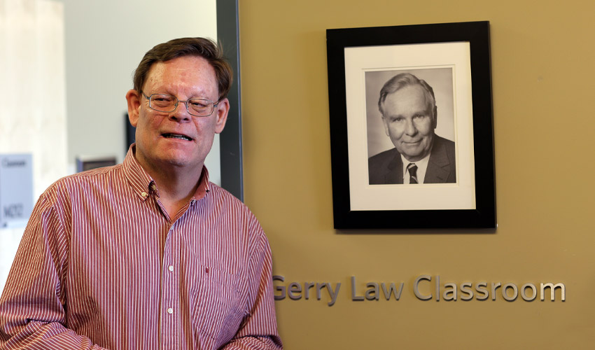 Jaime Law poses with a photo of his father, Gerry, at the opening of the Gerry Law Classroom.