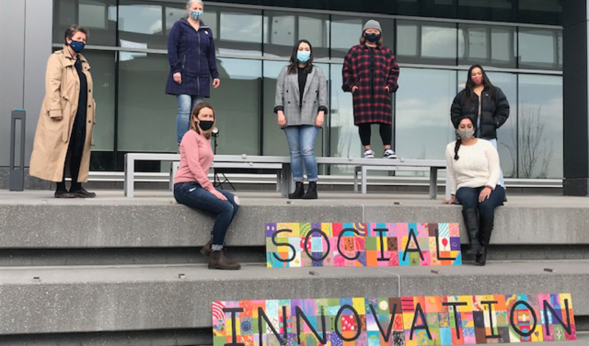 Catherine Pearl, Wendy Lees, Danika Dinko, Kat Bravo, Ashley Villaflores, Roshni McCartney, Ivy Daminan standing in front of the Riddell Library and Learning Centre.