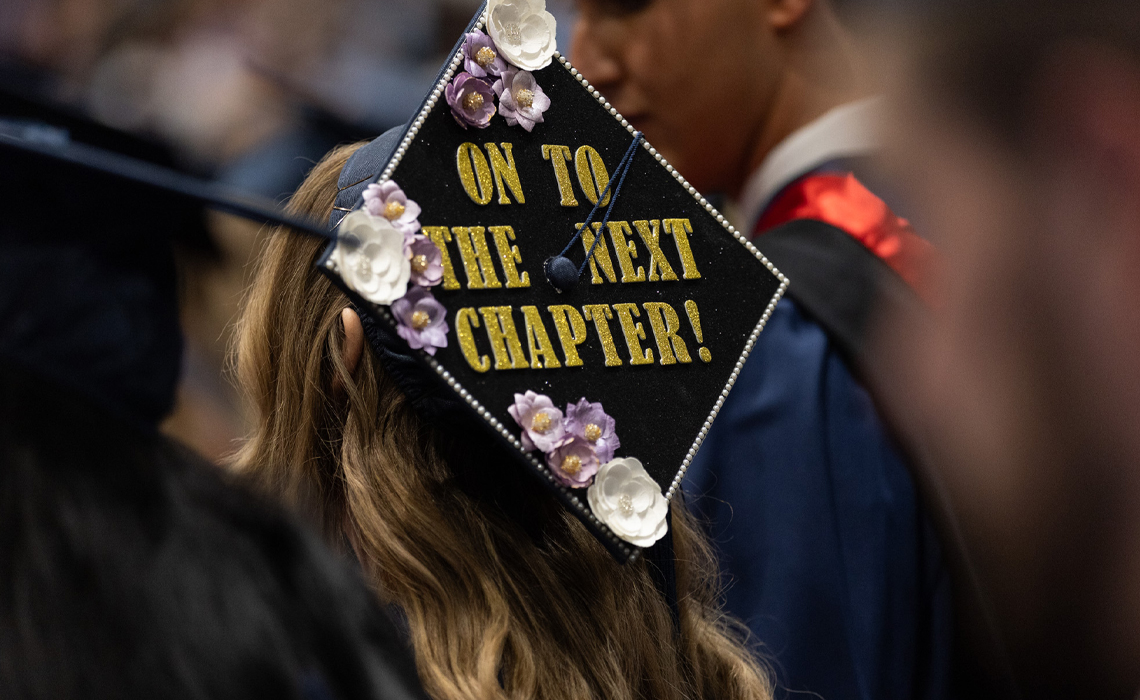 A decorated graduation cap featuring the words: on to the next chapter.