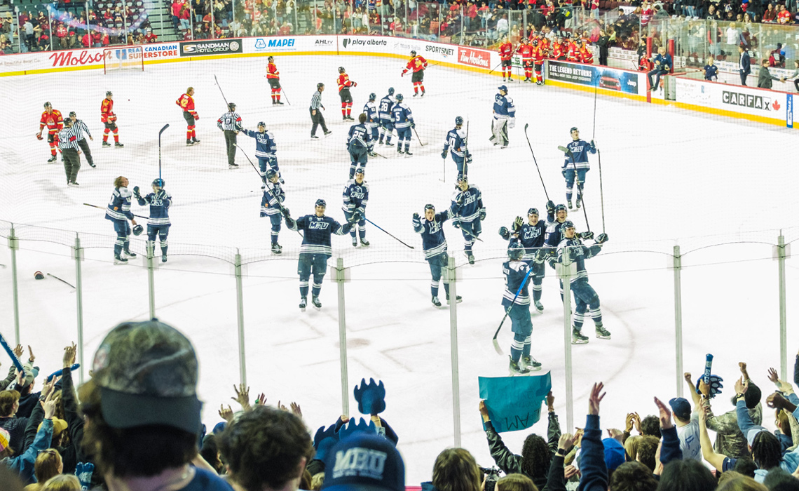 Cougars men’s hockey players raise their sticks in triumph at the Scotiabank Saddledome following a hard-fought battle against the University of Calgary Dinos.